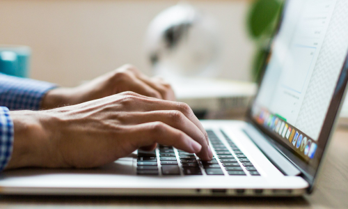 A close-up of hands typing on a laptop.