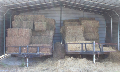 Hay stacked underneath a carport. 